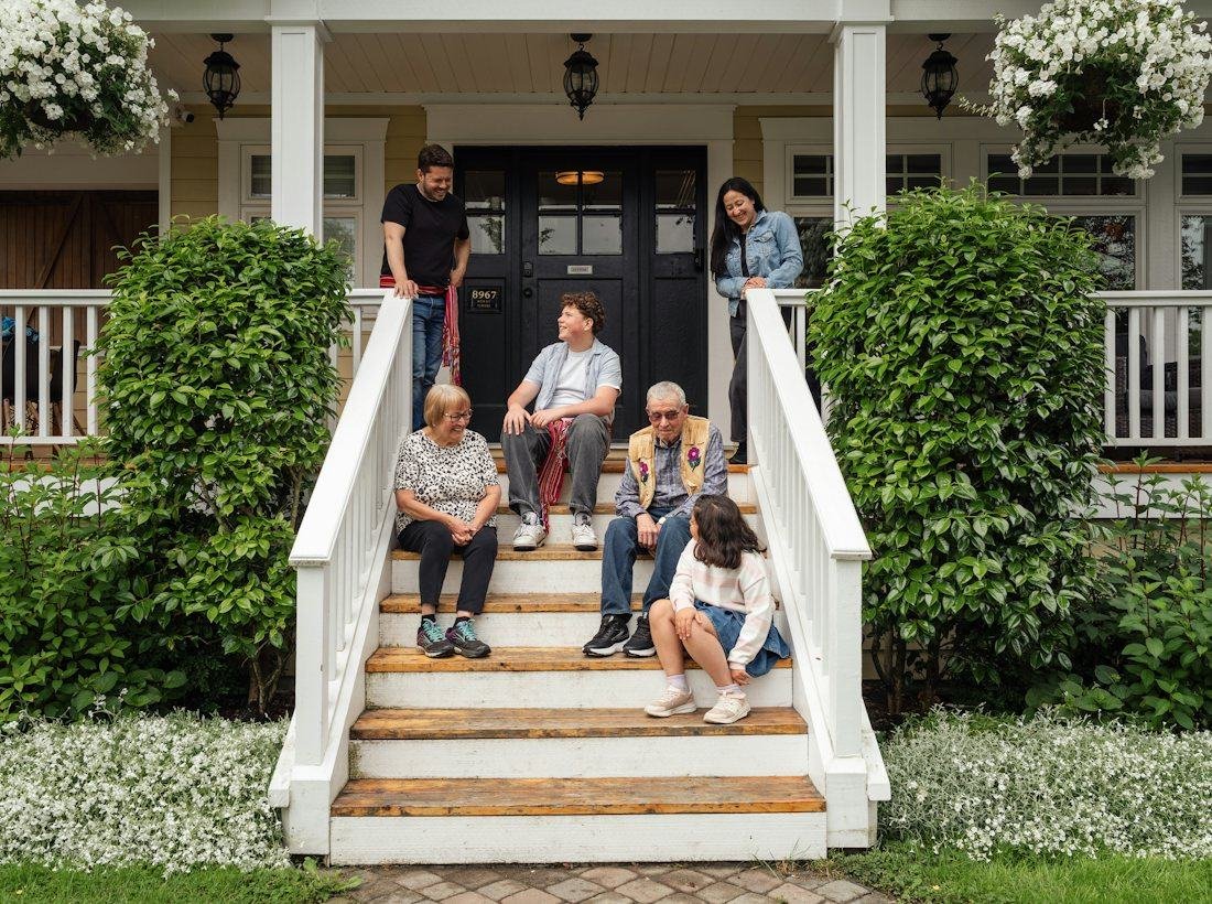 A family sitting together on the front steps of their home
