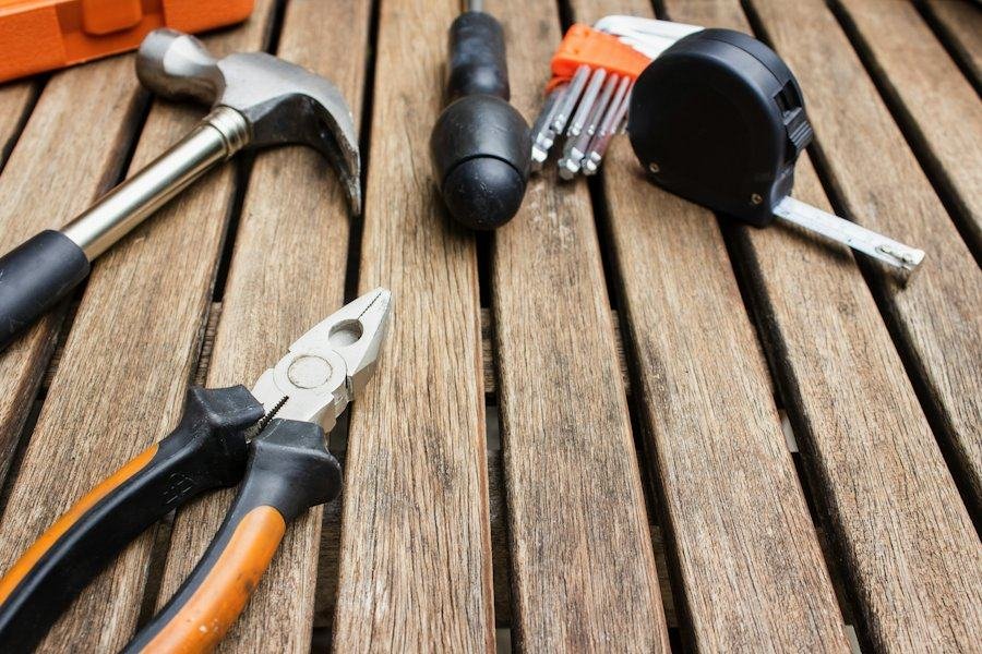 Hammer, pliers, screwdriver and tape measure on a wooden deck